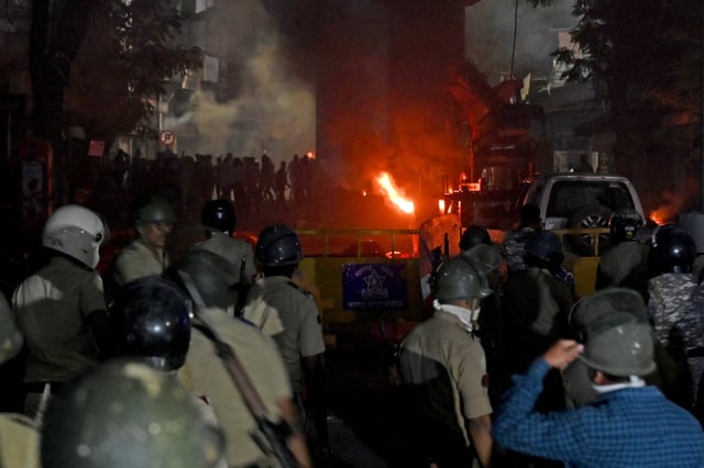 Members of police stand as vehicles burn after clashes erupted due to demands over removal of the tomb of Mughal emperor Aurangzeb, in Nagpur, India, March 17, 2025. REUTERS/Stringer