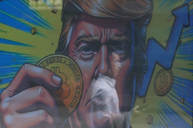 An illustration featuring U.S. President-elect Donald Trump holding Bitcoin is displayed outside a cryptocurrency exchange store after Bitcoin soars above $100,000, in Hong Kong, China, December 5, 2024. REUTERS/Tyrone Siu/File Photo