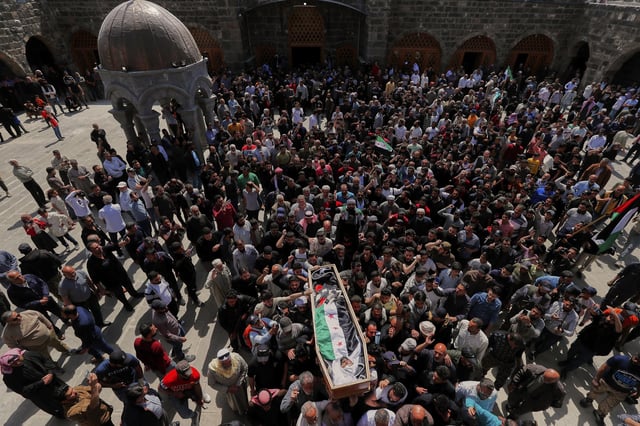 The body of Muhannad Akrad, one of three people killed in Israeli airstrikes on Monday, is carried for burial at the Omary mosque in Daraa, southern Syria, Tuesday, March 18, 2025. (AP Photo/Omar Sanadiki)