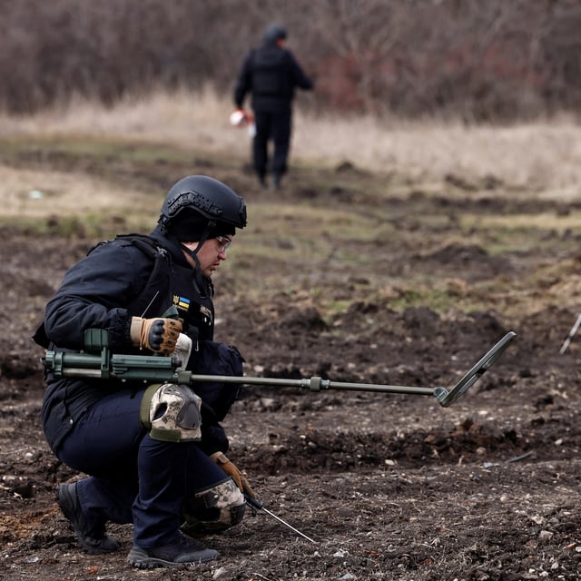 Members of the de-mining department of the Ukrainian Emergency Services survey an area of farmland and electric power lines for land mines and other unexploded ordnance for electricians to access power towers damaged by Russian strikes in order to repair them, amid Russia's invasion of Ukraine, in Korovii Yar, in the Eastern Donetsk region, Ukraine, March 20, 2023. REUTERS/Violeta Santos Moura