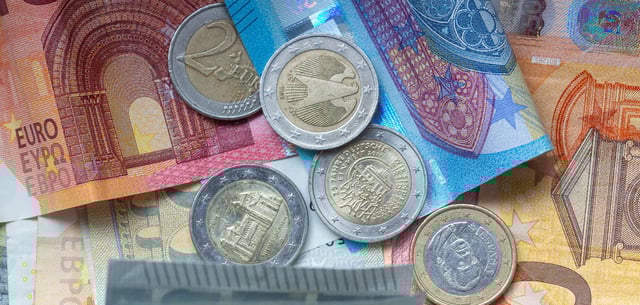 Euro-Münzen und Banknoten liegen aufeinander