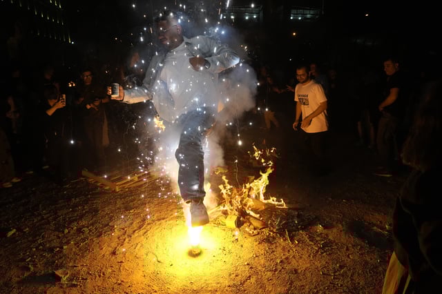 An Iranian man jumps over a firework celebrating Chaharshanbe Souri, or Wednesday Feast, an ancient Festival of Fire on the eve of the last Wednesday of the Persian year, in Tehran, Iran, Tuesday, March 18, 2025. Iranians celebrate their new year, or Nowruz, with arrival of the spring. (AP Photo/Vahid Salemi)