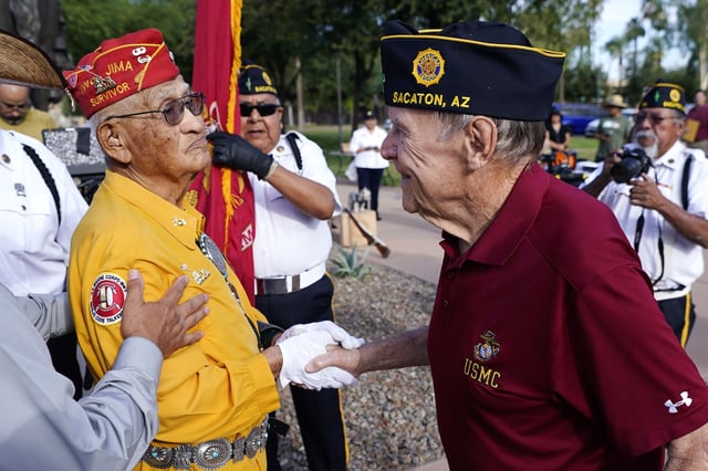 FILE - Navajo Code Talker Thomas Begay, left, shakes hands with Ron Enderle, right, a U.S. Marine veteran from the Korean War era, at the Arizona State Navajo Code Talkers Day ceremony, Aug. 14, 2022, in Phoenix. (AP Photo/Ross D. Franklin, File)
