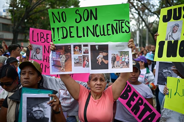 A family member of a Venezuelan deported from the US to El Salvador holds a sign that reads "They are not criminals" during a march demanding their release, in Caracas, Venezuela, on March 18, 2025.