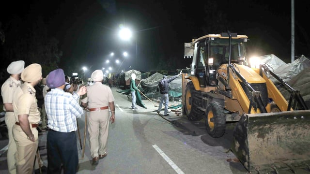 A backhoe loader being used to dismantle temporary structures set up by agitating farmers during an eviction drive by the Punjab Police to remove them from the Shambhu border, in Patiala district, Wednesday night, March 19, 2025.