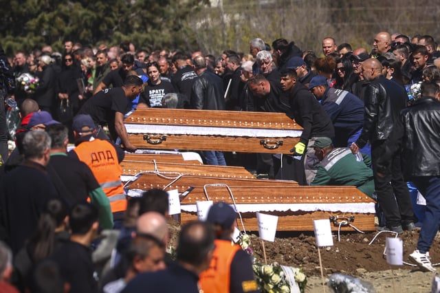 Coffins are placed next to the graves as people gather at a cemetery for the funeral ceremony of the victims of a massive nightclub fire in the town of Kocani, North Macedonia, Thursday, March 20, 2025. (AP Photo/Armin Durgut)