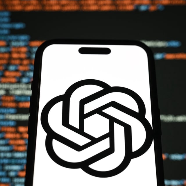 chat gpt on a phone screen in front of a blurry screen of code