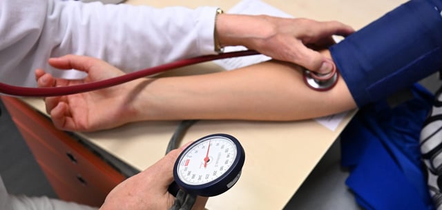 Ein Arzt misst in einer Bereitschaftspraxis in einem Krankenhaus bei einer Patientin den Blutdruck
