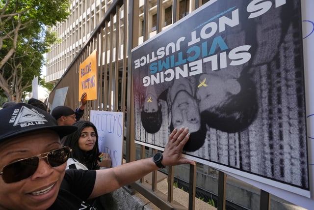 Supporters place signs on a fence outside of the Clara Shortridge Foltz Criminal Justice Center during a press conference regarding developments in the Menendez brothers case Thursday, March 20, 2025, in Los Angeles. (AP Photo/Damian Dovarganes)