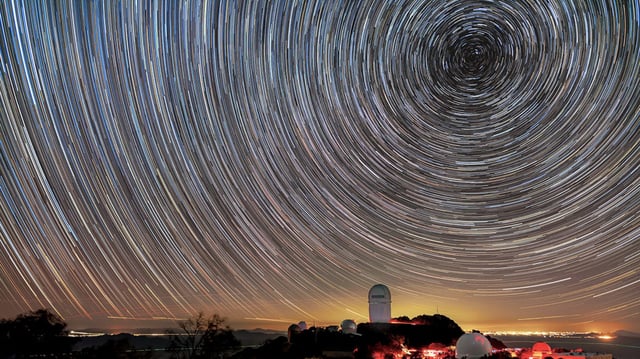 DESI maps distant objects to study dark energy. The instrument is installed on the Mayall Telescope, shown here beneath star trails.