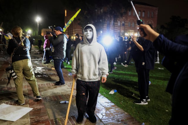 A person wearing a mask stands as pro-Palestinian protesters face off with CHP officers near an encampment on the University of California, Los Angeles (UCLA) campus, amid the ongoing conflict between Israel and the Palestinian Islamist group Hamas, in Los Angeles, California, U.S., May 1, 2024. REUTERS/David Swanson/File photo