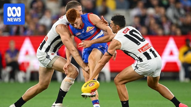 Ed Richards kicks the ball as two Collingwood players close him down