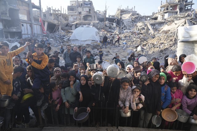 Palestinians wait for donated food at a distribution center in Beit Lahiya, northern Gaza Strip, Sunday, March 16, 2025. (AP Photo/Abdel Kareem Hana)