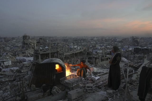 Ali Marouf and his mother Aisha cook on a fire on the roof of their house, which was destroyed by the Israeli army's air and ground offensive, in Jabaliya, Gaza Strip, on Monday, March 17, 2025. (AP Photo/Jehad Alshrafi)
