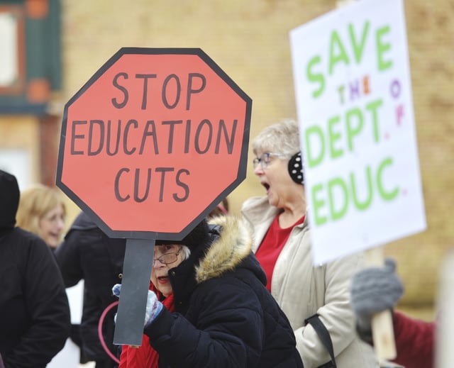 Dozens of people gather in downtown Niles, Mich., Thursday, March 20, 2025, to protest recent government cuts in the Department of Education.