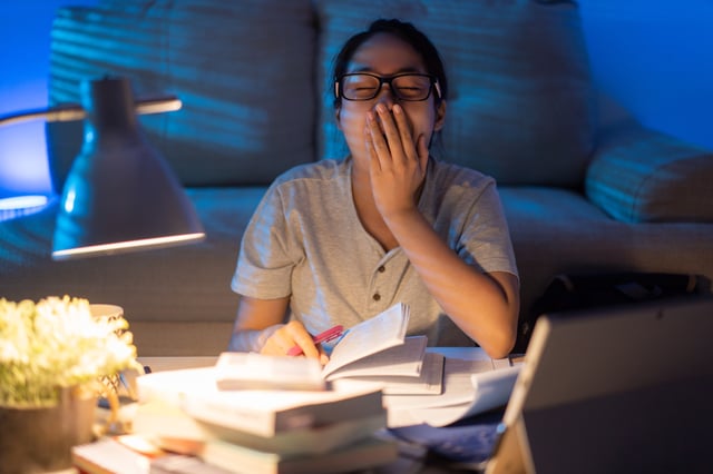 A stock image of a young woman yawning while working late at home.