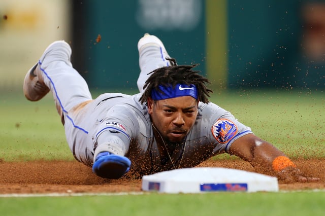 Dominic Smith #22 of the New York Mets dives safely into third base after stealing second and advancing on a throwing error by catcher J.T. Realmuto #10 of the Philadelphia Phillies during the sixth inning of a baseball game at Citizens Bank Park on June 26, 2019 in Philadelphia, Pennsylvania.