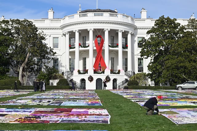 A red ribbon can be seen on the South Portico of the White House overlooking an AIDS Memorial Quilt display in the South Lawn of the White House before US President Joe Biden and First Lady Jill Biden delivers remarks to commemorate World AIDS Day on the South Lawn of the White House in Washington, DC, on December 1, 2024. 