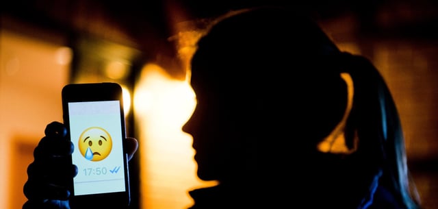 Ein junges Mädchen zeigt das Display eines Smartphones mit einem weinenden Emoji: Vor allem Schüler sind von persönlichen Angriffen im Internet betroffen