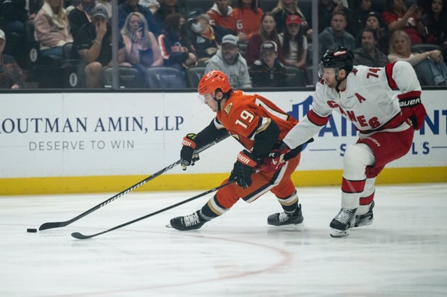 Ducks right wing Troy Terry (19) controls the puck as Carolina Hurricanes defenseman Jaccob Slavin (74) chases during the first period of an NHL hockey game, Sunday, March 23, 2025, in Anaheim, Calif. (AP Photo/Kyusung Gong)