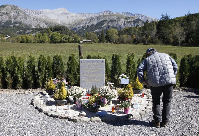FILE - A man pays his respect to the Germanwings victims in Le Vernet, in the French Alps, Sept. 24, 2015. (AP Photo/Lionel Cironneau, File)