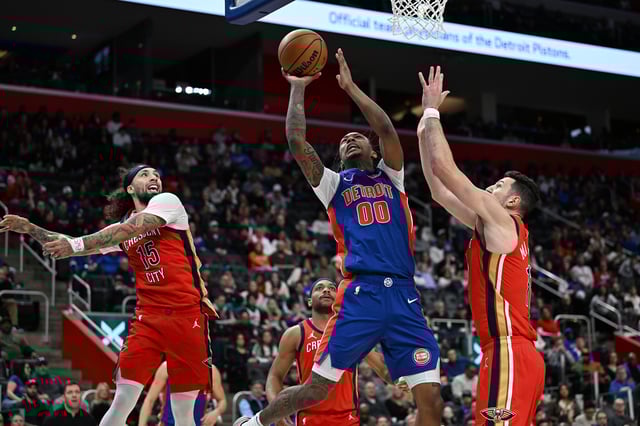 Mar 23, 2025; Detroit, Michigan, USA;  Detroit Pistons forward Ronald Holland II (00) drives between New Orleans Pelicans guard Jose Alvarado (15) and center Karlo Matkovic (17) to score a basket in the third quarter at Little Caesars Arena. Mandatory Credit: Lon Horwedel-Imagn Images