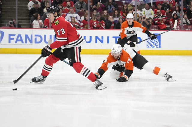 Mar 23, 2025; Chicago, Illinois, USA; Philadelphia Flyers center Sean Couturier (14) defends Chicago Blackhawks left wing Lukas Reichel (73) during the third period at United Center. Mandatory Credit: David Banks-Imagn Images