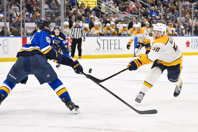 Mar 23, 2025; St. Louis, Missouri, USA;  Nashville Predators left wing Michael Bunting (58) shoots as St. Louis Blues defenseman Matthew Kessel (51) defends during the third period at Enterprise Center. Mandatory Credit: Jeff Curry-Imagn Images