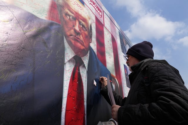 A man writes a slogan on a portrait of the U.S. President Donald Trump during a rally commemorating anniversary of Iran&#39;s 1979 Islamic Revolution that toppled the late pro-U.S. Shah Mohammad Reza Pahlavi and brought Islamic clerics to power, in Tehran, Iran, Monday, Feb. 10, 2025.