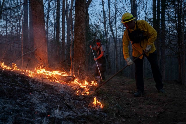 Troutman Fire Department firefighter Sam Mills (left) and Deputy Chief of Troutman Fire Department Jimmy Kestler (right) work a backburn preventative fire to stop the spread of the Deep Woods Fire on March 23, 2025 in Columbus, North Carolina.