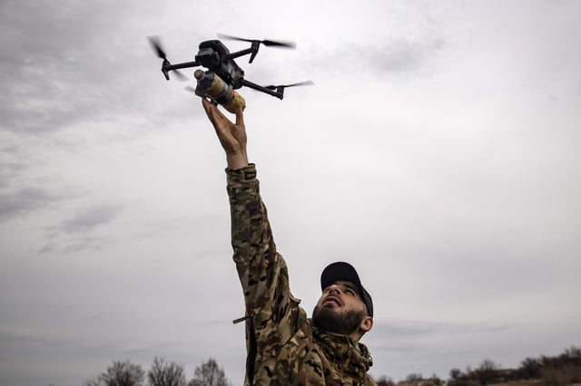 A Ukrainian soldier holds an FPV drone at arm’s length during military exercises on March 15, 2025 in Donetsk Oblast, Ukraine.