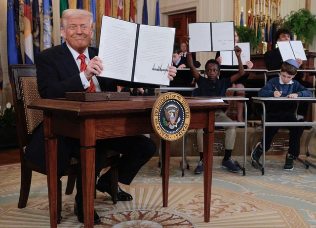 U.S. President Donald Trump holds up the signed executive order in the White House on March 20, 2025 in Washington, DC.