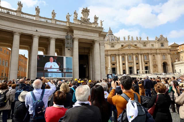 People watch Pope Francis during his first public appearance in five weeks, on the day of his discharge from Gemelli Hospital, on a big screen in St. Peter's Square, at the Vatican, March 23, 2025. REUTERS/Ciro de Luca