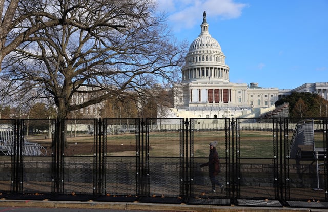 A pedestrain walks behind the security fencing which encircles the U.S. Capitol building in Washington, U.S., January 4, 2025.  REUTERS/Fabrizio Bensch/File Photo