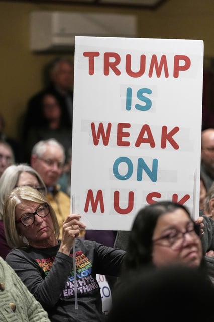 Carla Raupp holds a sign during a town hall meeting at the George Culver Community Library Thursday, March 6, 2025, in Sauk City, Wis. (AP Photo/Morry Gash)