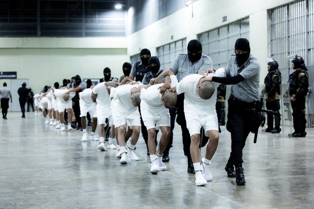 Salvadoran police officers escort alleged members of the Venezuelan gang Tren de Aragua recently deported by the U.S. government to be imprisoned in the Terrorism Confinement Center (CECOT) prison, as part of an agreement with the Salvadoran government, in Tecoluca, El Salvador, in this handout image obtained March 16, 2025. Secretaria de Prensa de la Presidencia/Handout via REUTERS/File Photo