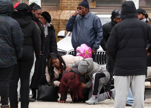 Kyana Love, center, drops to the ground as she mourns 16-year-old daughter, Kaylah Love, before the start of a balloon release outside of Manley Career Academy High School on March 23, 2025 in Chicago. (Stacey Wescott/Chicago Tribune)