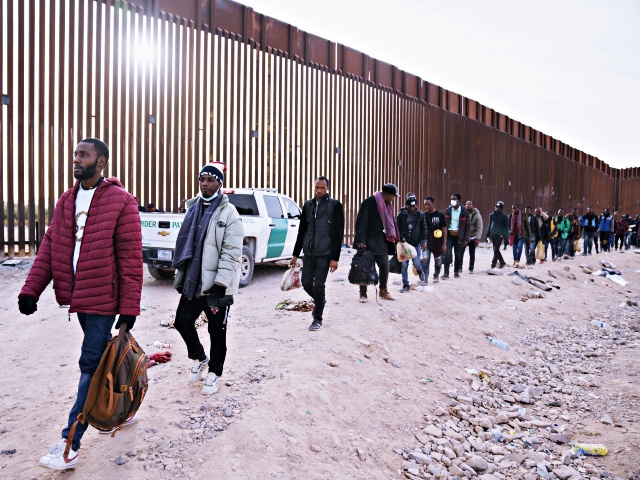 Migrants walk beside the US-Mexico border fence in Lukeville, Arizona, US, on Monday, Dec. 11, 2023. An influx of migrants crossing the border unlawfully around remote Lukeville, Arizona, has overwhelmed US border officials causing them to close the official port of entry in order to direct resources to processing the unlawful arrivals. Photographer: Eric Thayer/Bloomberg