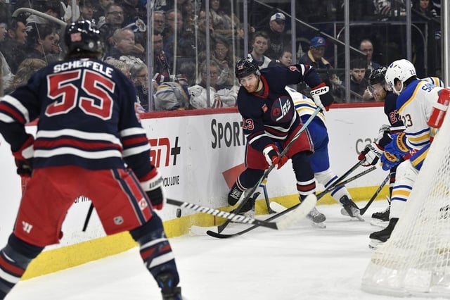 Winnipeg Jets' Gabriel Vilardi (13) passes the puck to Mark Scheifele (55) behind the Buffalo Sabres net during second period NHL action in Winnipeg, Sunday March 23, 2025. THE CANADIAN PRESS/Fred Greenslade