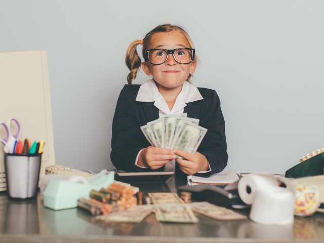 Child at desk with a lot of money
