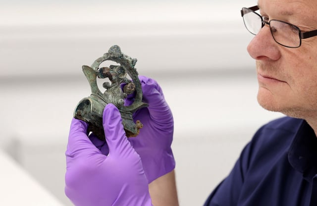 Tom Moore, head of archaeology at Durham University, holding a decorative copper alloy finial, which was part of the hoard.