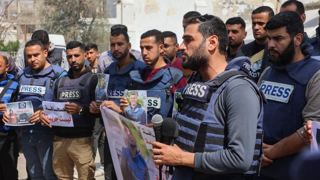 Palestinian journalists lift placards during a rally in protest of the killing of fellow reporters Hussam Shabat and Muhammad Mansour.