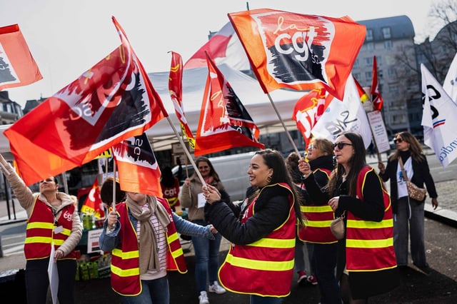 Des employés de la Société Générale brandissent des drapeaux de la CGT alors qu'ils participent à une manifestation devant une agence , le 25 mars 2025, à Lille.