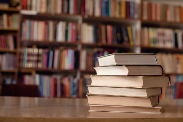 A close-up of books sitting on a desk in a library.
