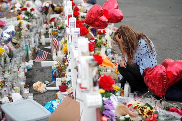 Gloria Garces kneels in front of crosses at a makeshift memorial, in El Paso, Texas, on Aug. 6, 2019.
