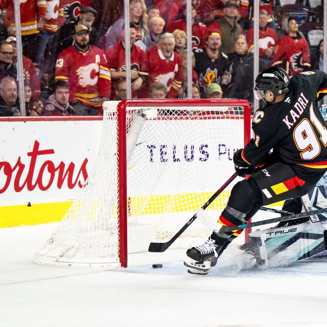 Mar 25, 2025; Calgary, Alberta, CAN; Calgary Flames center Nazem Kadri (91) scores the game-winning goal on Seattle Kraken goaltender Joey Daccord (35) during the overtime period at Scotiabank Saddledome. Mandatory Credit: Brett Holmes-Imagn Images