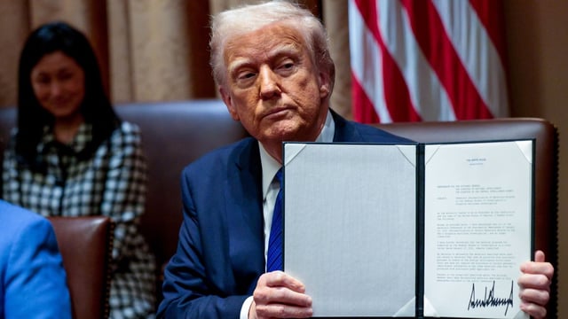 US President Donald Trump displays a signed executive order during a meeting with US ambassadors in the Cabinet Room of the White House in Washington, DC, US, on Tuesday, March 25, 2025. 