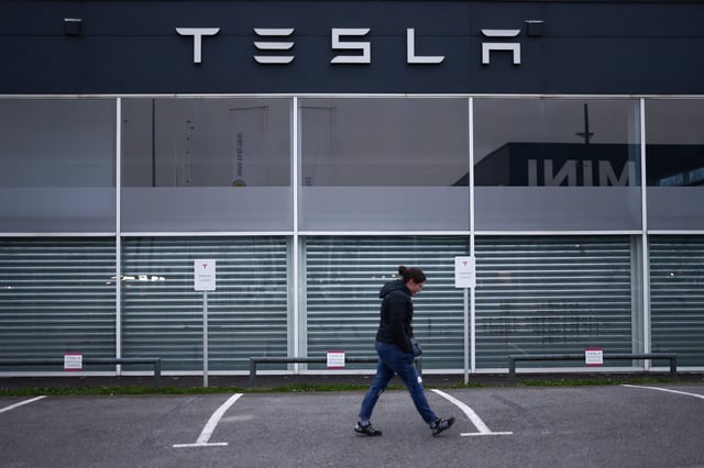 A woman walks in front of a Tesla dealership in Saint-Herblain near Nantes, France, March 25, 2025. REUTERS/Stephane Mahe/File Photo