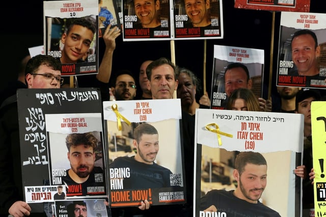 Relatives and supporters hold portraits of Israeli hostages, including Guy Gilboa-Dalal, pictured bottom left