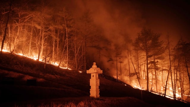 A wildfire is seen next to a stone lantern of family tomb in Andong on March 26, 2025..